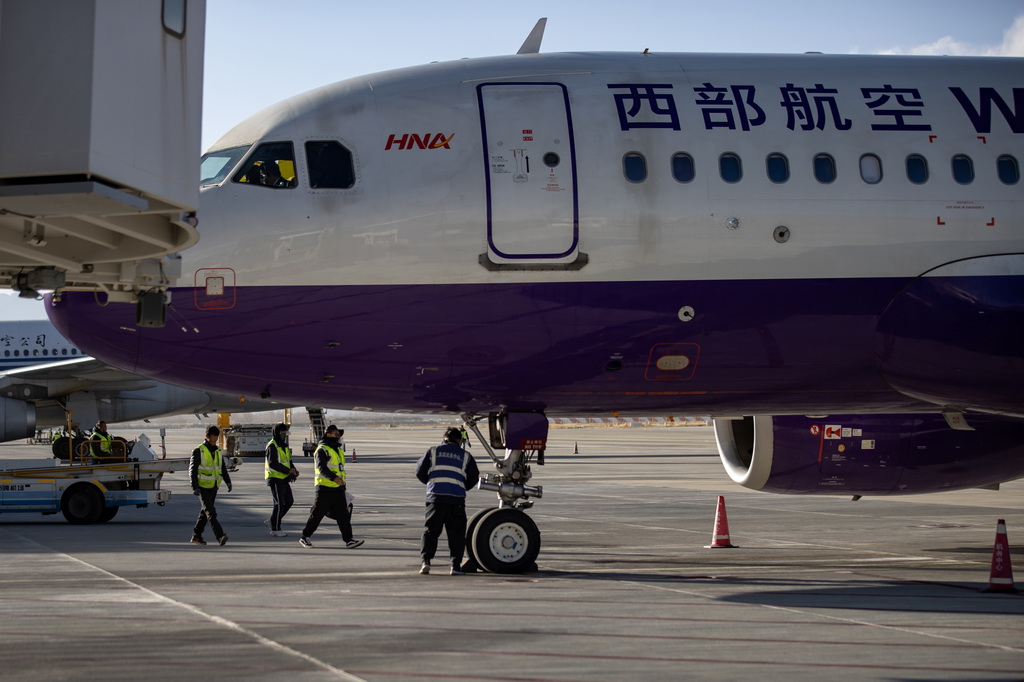 12月25日，执飞拉萨-重庆-新加坡国际新航线首飞任务的西部航空PN6425客运航班在拉萨贡嘎国际机场停靠廊桥。新华社记者 姜帆 摄