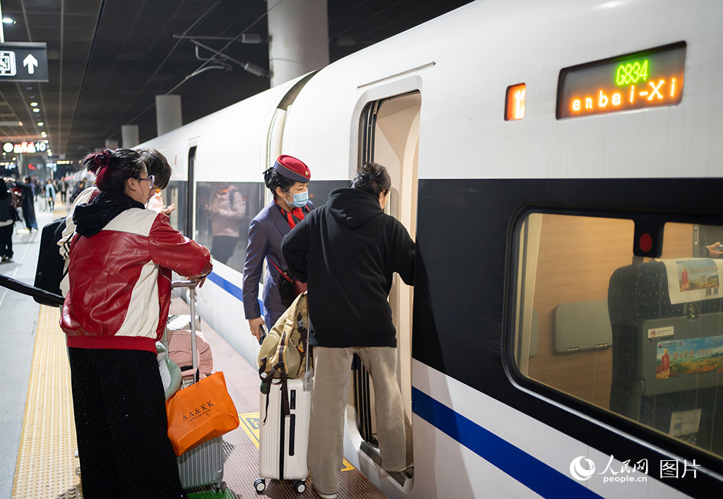 2025年春运首日，深圳北站，乘务员协助旅客登车。人民网 江佳玲摄