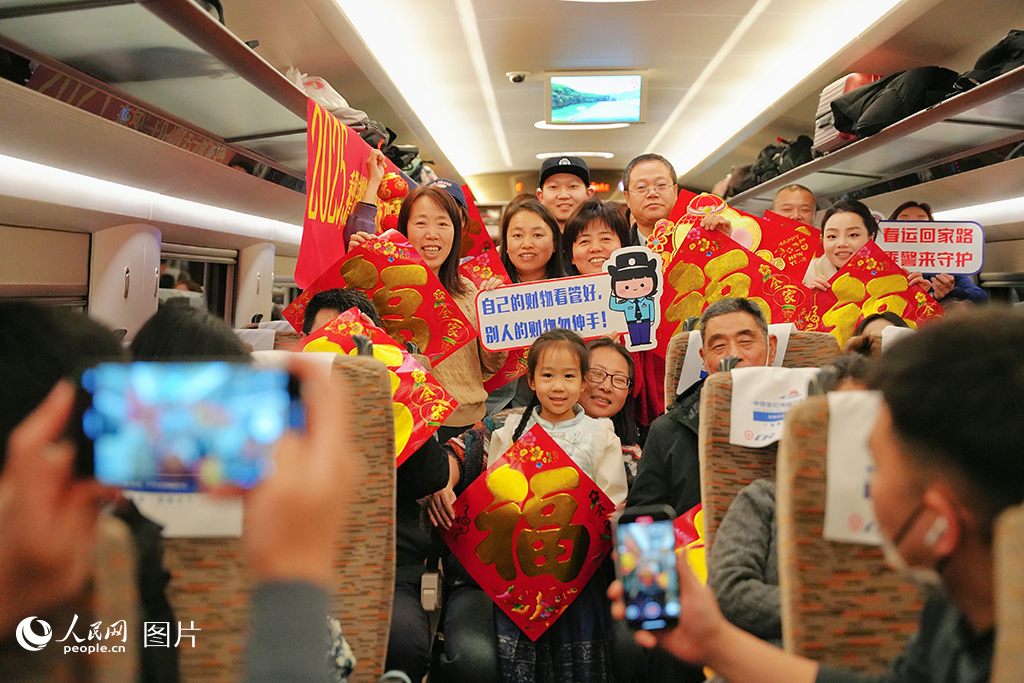 1月13日，在G486次列车上石家庄铁路公安处民警，为旅客送“福”字、普及乘车安全知识并合影留念。人民网记者 周博摄