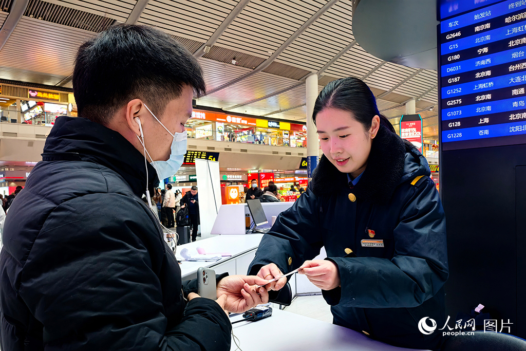 1月13日，济南西站客服中心的客运员根据旅客的换乘需求，在提示卡上标记路线，帮助旅客便捷换乘。人民网记者 刘祺摄