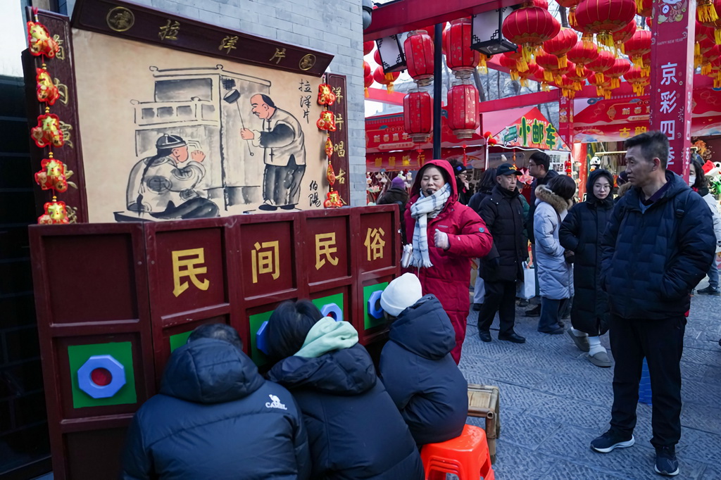 1月29日，游客在位于北京中轴线上的前门大街步行街区域观看拉洋片。新华社记者 鞠焕宗 摄