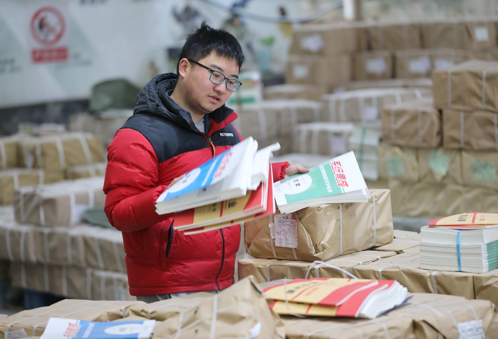 2月10日，在湖南省永州市道县新华书店仓库，工作人员在清点、分发教材。新华社发（何红福摄）