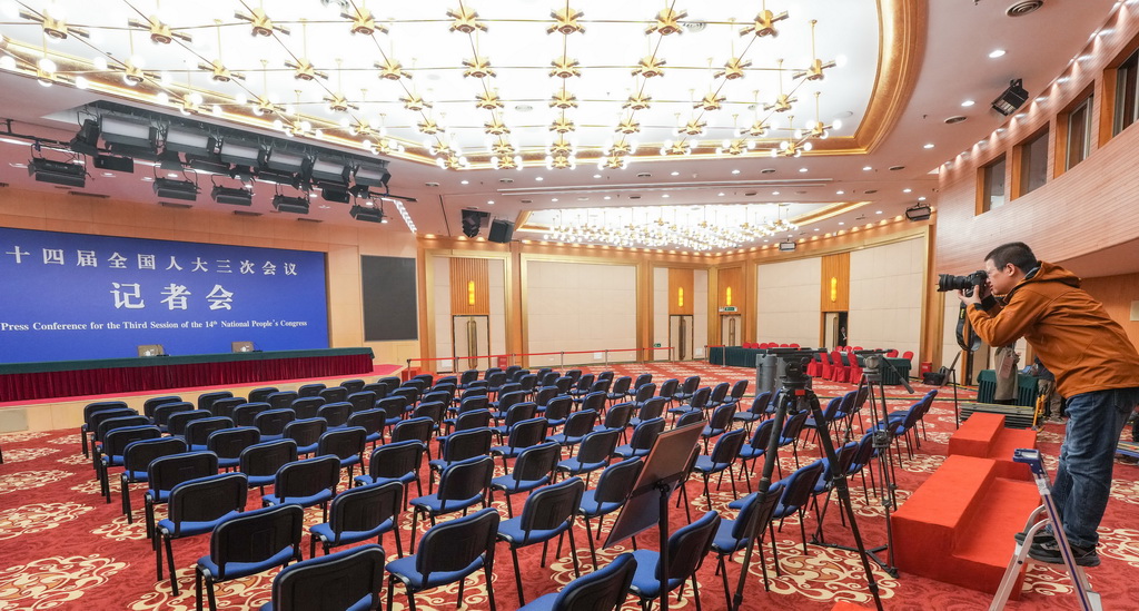 2月27日，一名记者在全国两会新闻中心新闻发布厅拍摄。