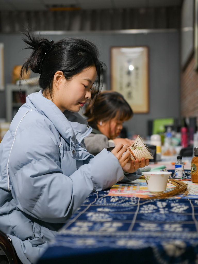 白梓忆（前）在编制“熊猫抱竹”盖碗茶杯（3月7日摄）。新华社记者 王曦 摄
