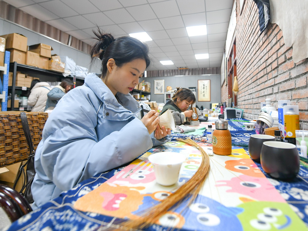 白梓忆（前）在编制“熊猫抱竹”盖碗茶杯（3月7日摄）。新华社记者 王曦 摄