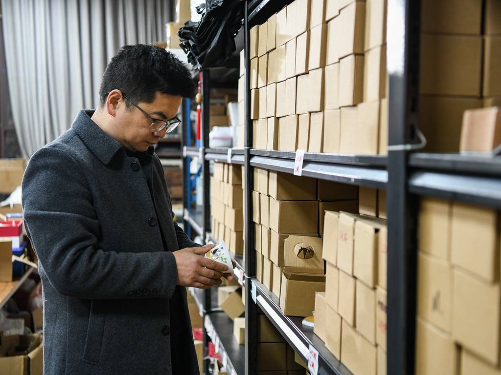 白静波在库房查看即将入库的“熊猫抱竹”盖碗茶杯成品（3月7日摄）。新华社记者 王曦 摄