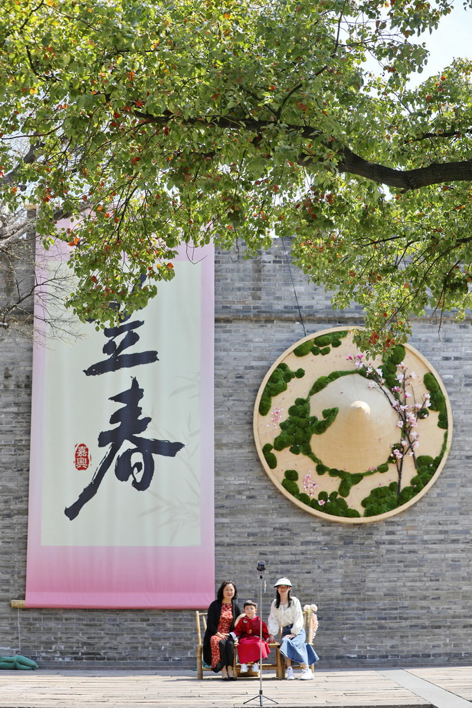 3月22日，在浙江省嘉兴市南湖区子城遗址公园，游人在古城墙巨型“笠春”“斗笠”创意装饰前拍照。新华社发（金鹏摄）