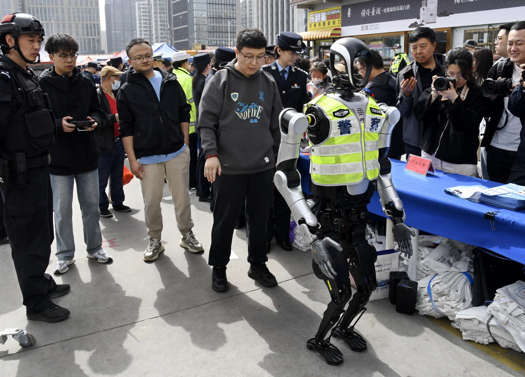 3月24日，警用机器人在活动现场与观众互动。