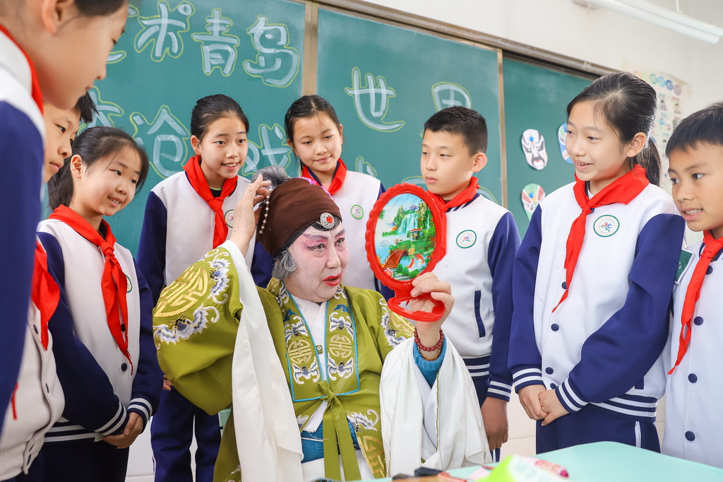 3月25日，在山东青岛北山小学开展的“艺术青岛·李沧有戏”主题活动中，柳腔演员向学生展示戏曲脸谱绘制。新华社发（张鹰摄）