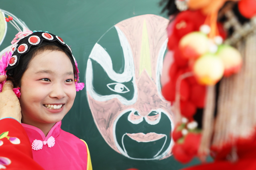3月25日，在河北省唐山市丰润区泉河头镇团山子小学，评剧演员帮助学生整理头饰。新华社发（朱大勇摄）