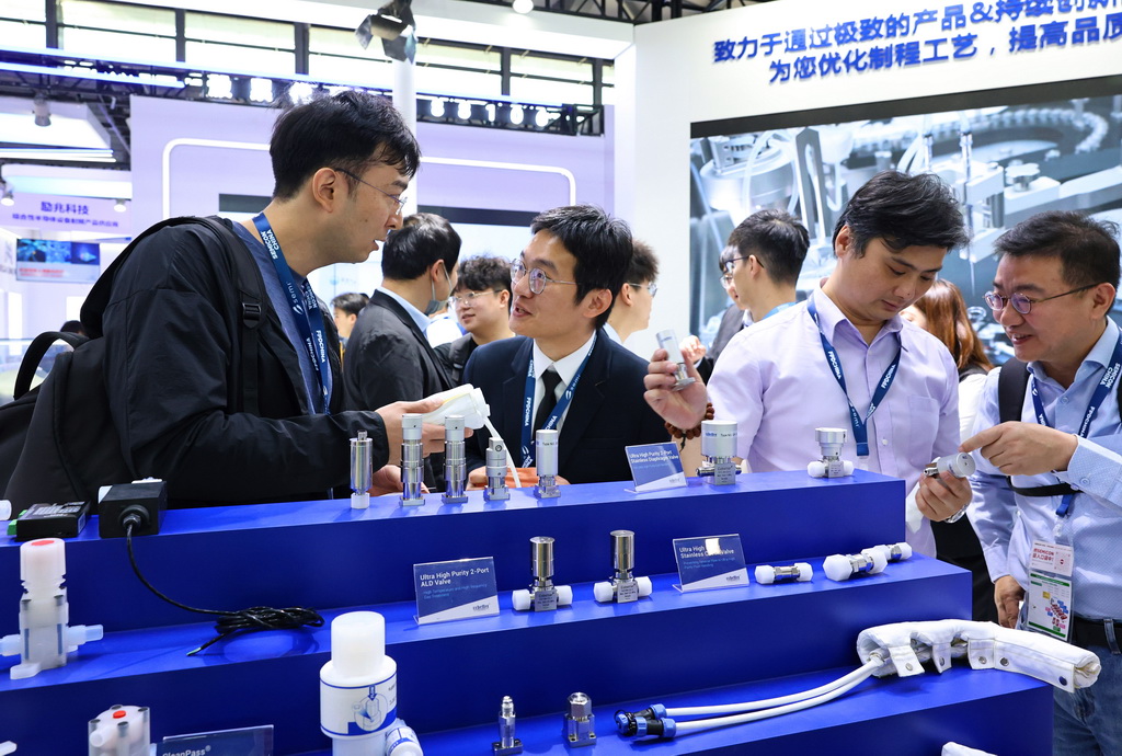 3月26日，参观者在一组集成电路制造设备阀门零部件展品前交流讨论。