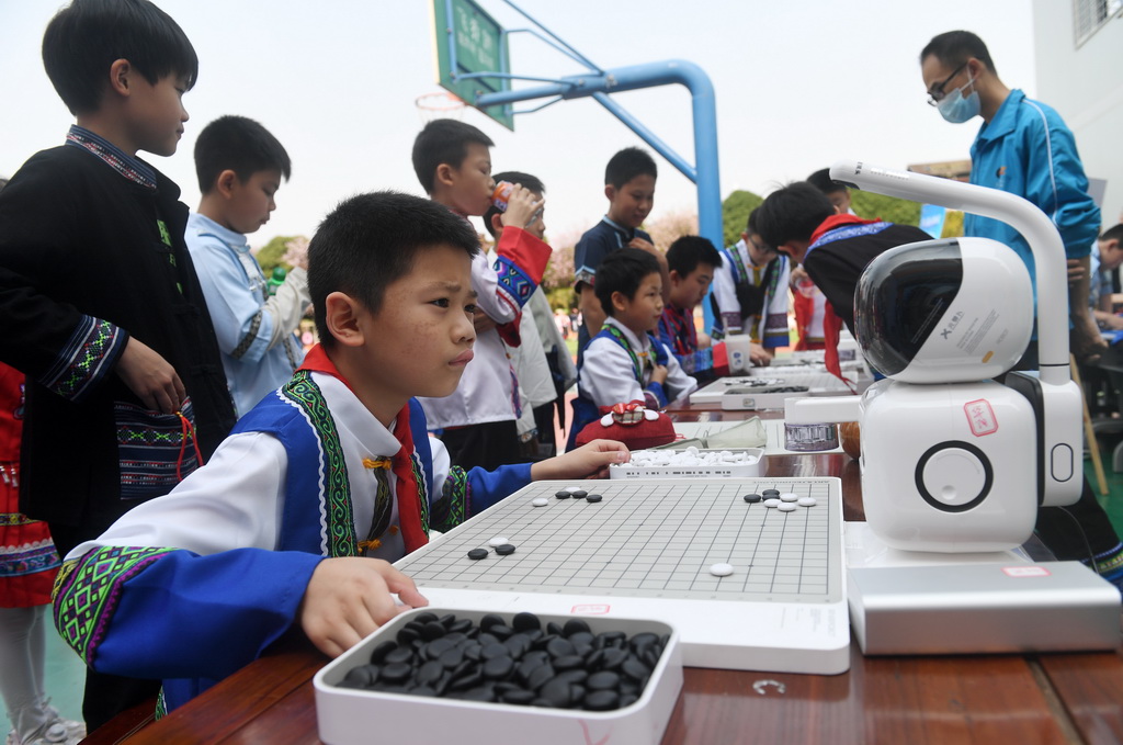 3月27日，在广西南宁市滨湖路小学，学生在和机器人下围棋。新华社记者 陆波岸 摄