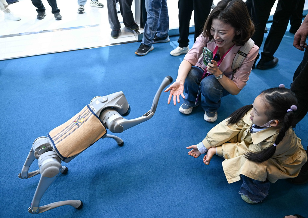 4月14日，观众在第五届消博会宇树科技展台与机器狗握手。新华社记者 蒲晓旭 摄