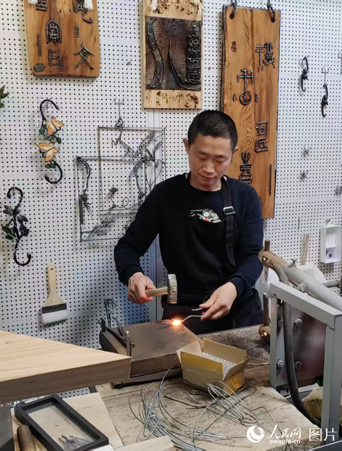 西河古镇铁画工作室内，西河铁画匠人陶绍军在制作铁画。陶绍军制作铁画已有22年的时间，从他手中制作出去的成品有很多件，小到梅兰竹菊四条屏、各种赛事的吉祥物，大到挂满一面墙的大件。