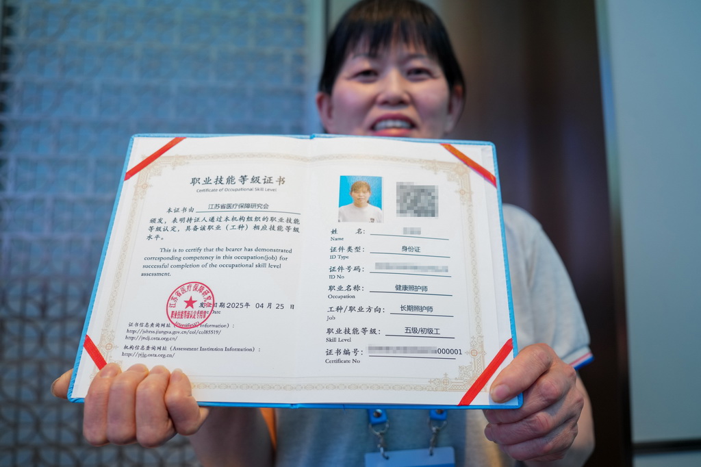 4月28日，长期照护师代表展示自己的“000001”编号证书。