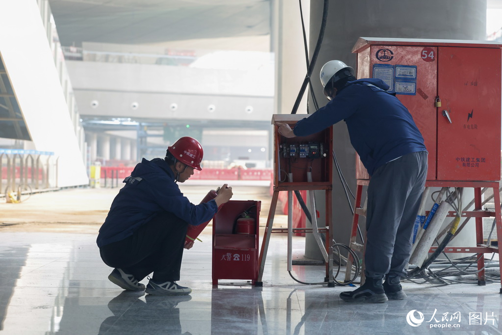施工人员在现场检查灭火器、配电箱等装置，确保施工安全。