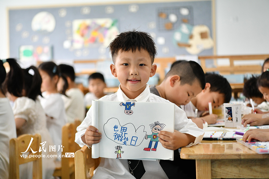 2025年5月7日，安徽省阜阳市阜南县骆寨社区幼儿园的孩子展示自己绘制心中的笑脸。吕乃明摄（人民图片网）