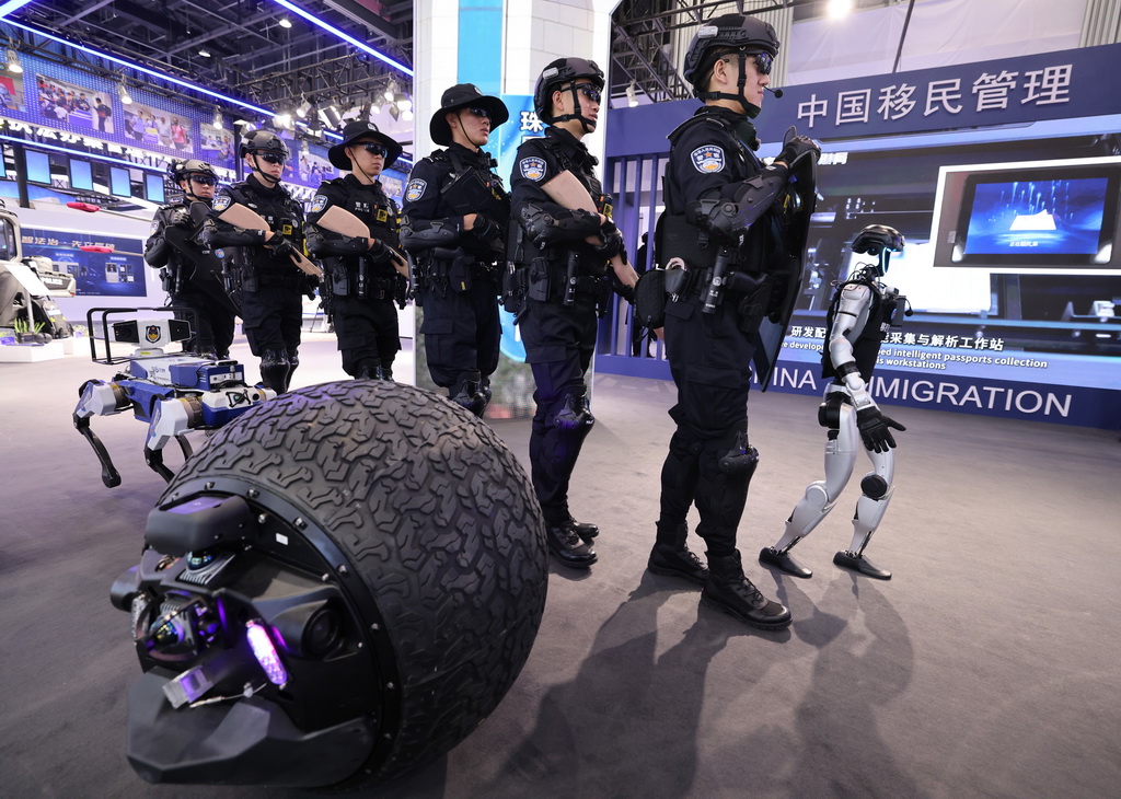 5月14日,在第十二届中国国际警用装备博览会移民管理装备展区,民警和球形机器人、警用机器狗和具身人形智能警务机器人(右一)一起进行巡逻演练。新华社记者 殷刚 摄