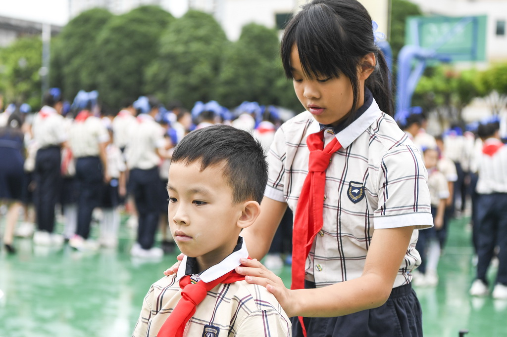 5月30日，在广西南宁市滨湖路小学教育集团滨湖校区少先队员入队仪式上，高年级学生为新队员戴红领巾。