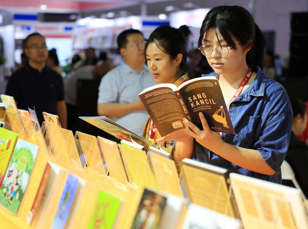 6月18日，观众在翻阅主宾国马来西亚展区的图书。