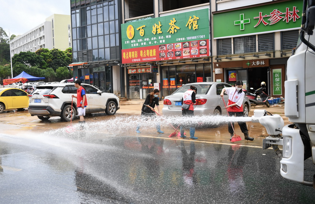 6月19日，在广东省肇庆市怀集县城的碧桂园玖珑湾小区外，志愿者配合水车清洗街道。