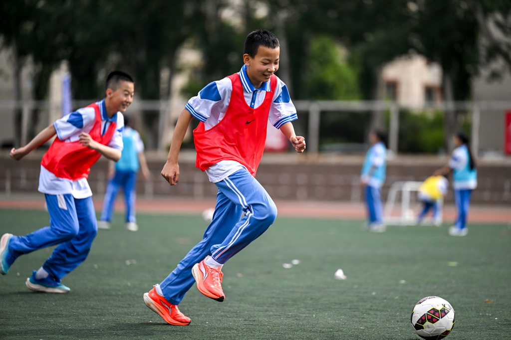6月25日，中学生们在活动中参加校园足球课。