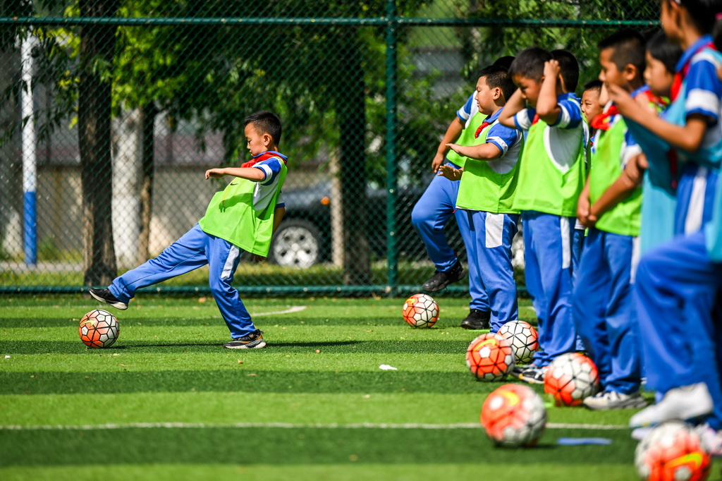 6月25日，小学生们在活动中参加校园足球课。