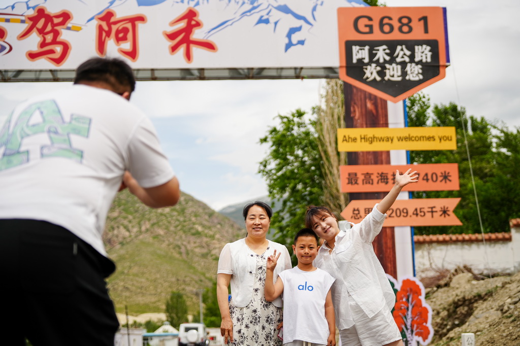 6月30日，游客在阿禾公路一处打卡点拍照留念。