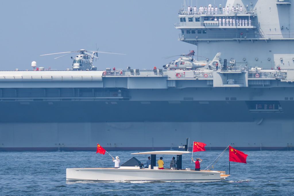 7月7日,市民乘船手举国旗敬礼,为山东舰送行。新华社记者 朱炜 摄
