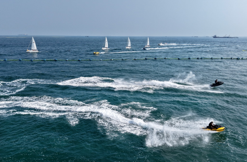 青岛老龙湾海域，摩托艇参加海上巡游活动（7月10日摄，无人机照片）。