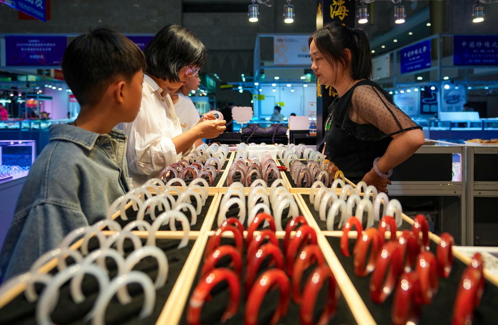 7月10日，消费者（左二）在昆明石博会上挑选玉石。