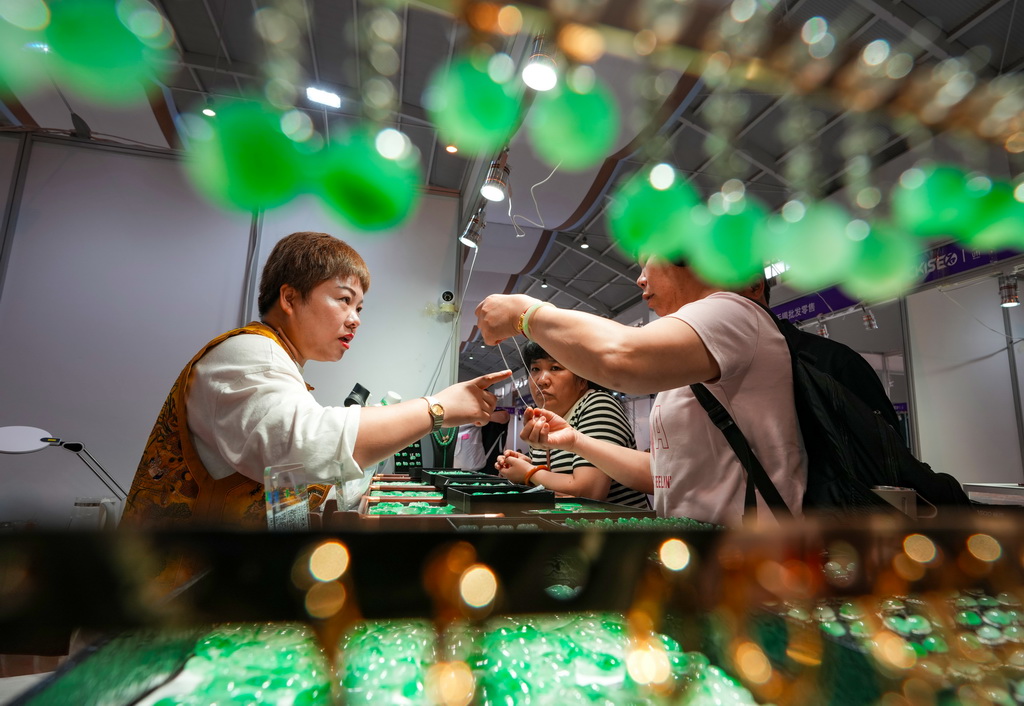 7月10日，参展商（左）在昆明石博会上向消费者介绍玉石。