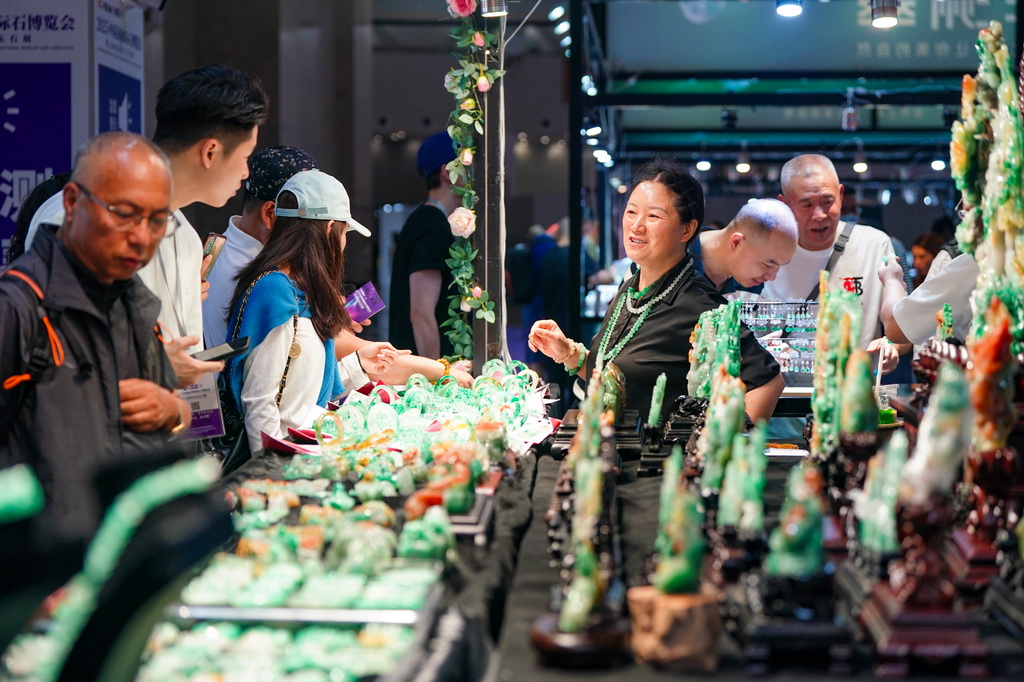 7月10日，参展商（右三）在昆明石博会上售卖玉石。