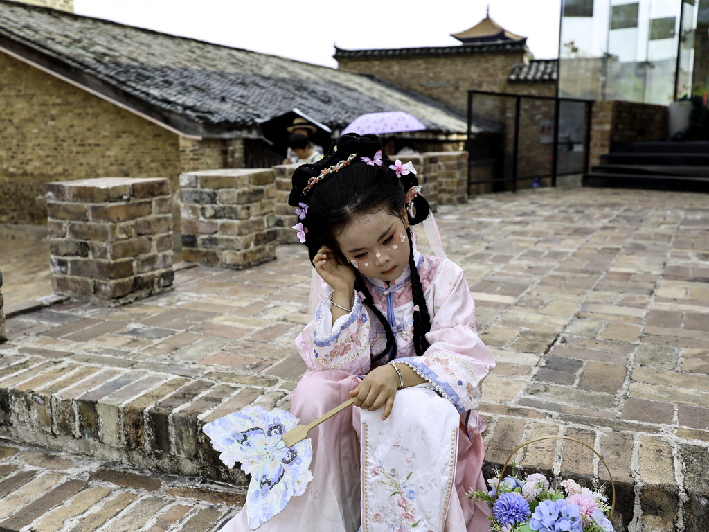 7月13日，一名小游客在江西省景德镇市陶阳里历史文化街区休憩。