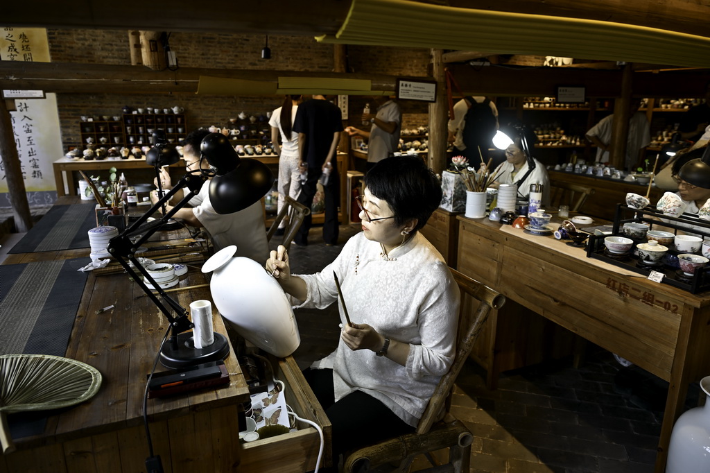 7月13日，在江西省景德镇市陶阳里历史文化街区，包括国家级非遗传统粉彩瓷制作技艺传承人傅长敏（中）在内的一批陶瓷手工技艺传承人进行现场创作。