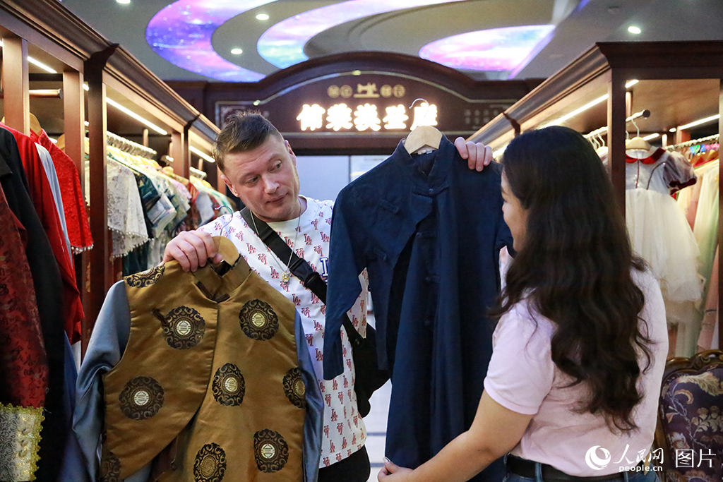 2025年6月26日，上海千古情景区，一位外国游客正在挑选中国风服装。人民网记者 龚莎摄