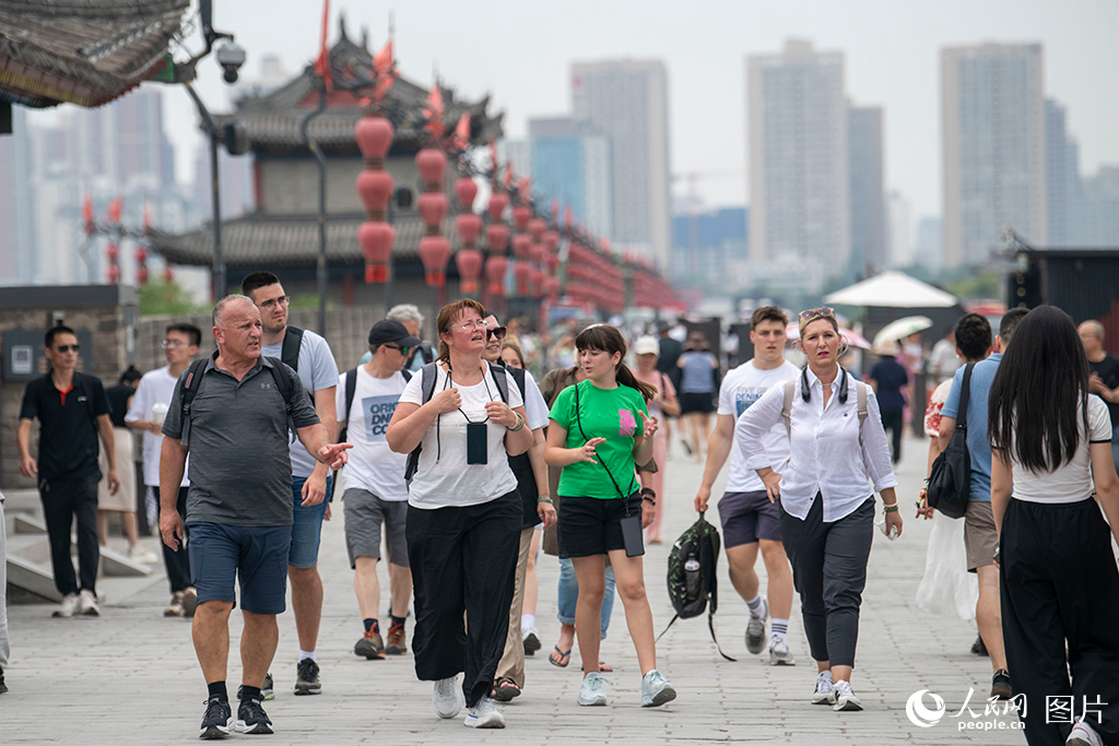 2025年6月19日，外国游客在陕西西安城墙上观光游览，感受千年古都文化魅力。人民网记者 翁奇羽摄