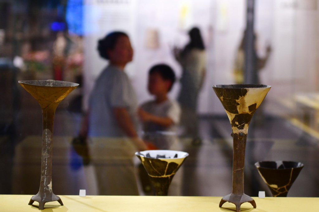 7月14日，游客在大汶口遗址博物馆内参观出土陶器。