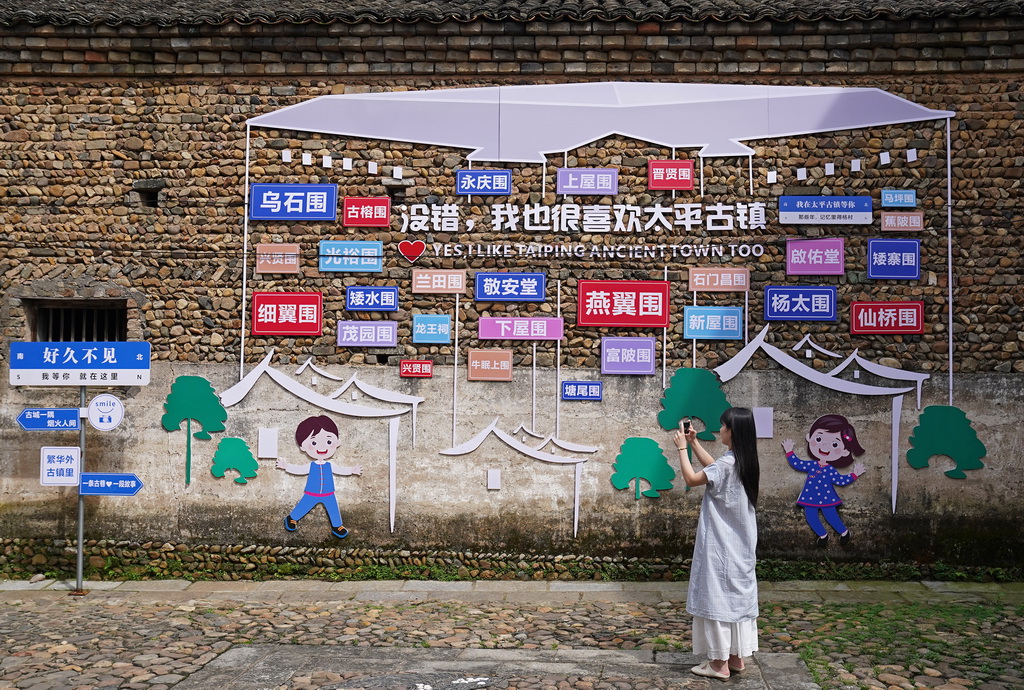 游客在龙南市杨村镇燕翼围周边游览（6月19日摄）。