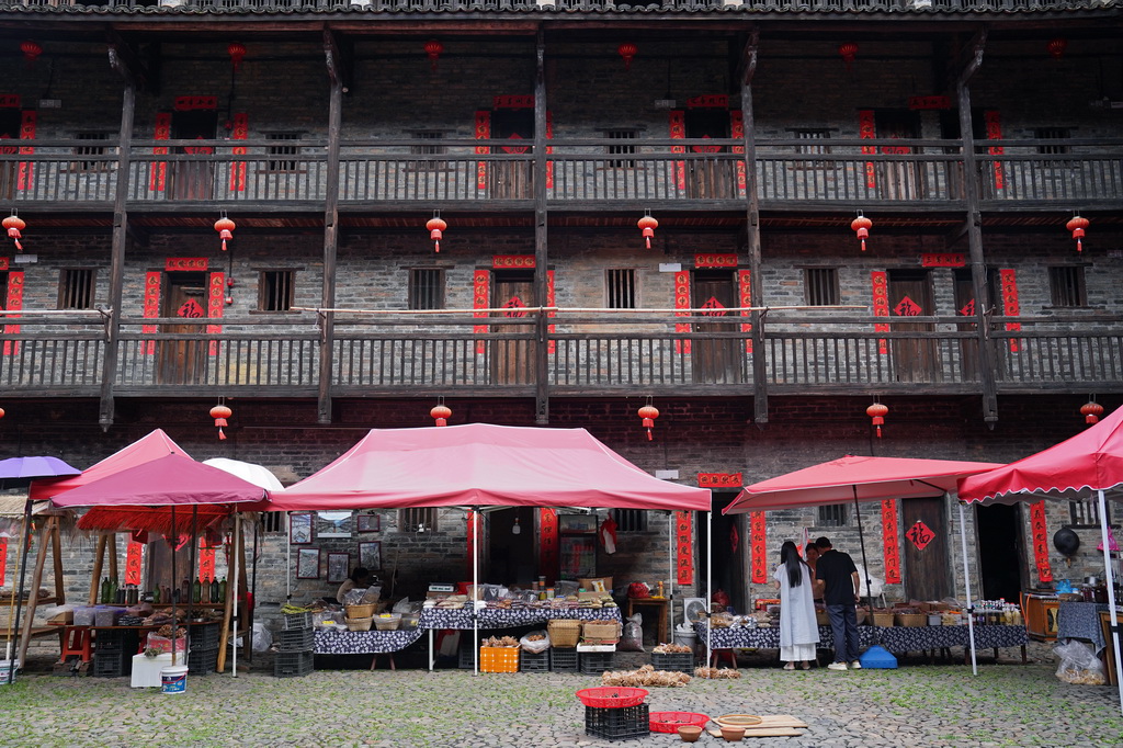 游客在龙南市杨村镇的燕翼围内选购村民的土特产（6月19日摄）。