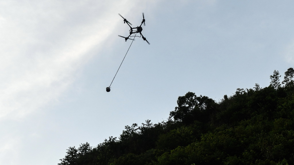 桥隧工人遥控无人机给隧道山体上的施工点运送混凝土（7月15日摄）。