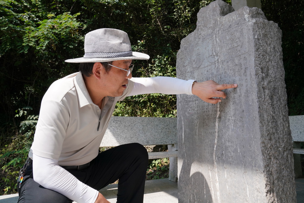 7月14日,在青泥岭上,徽县博物馆文博副研究馆员曹鹏雁在介绍一块刻有“远通吴楚”字样的清代石碑。新华社记者 马宁 摄