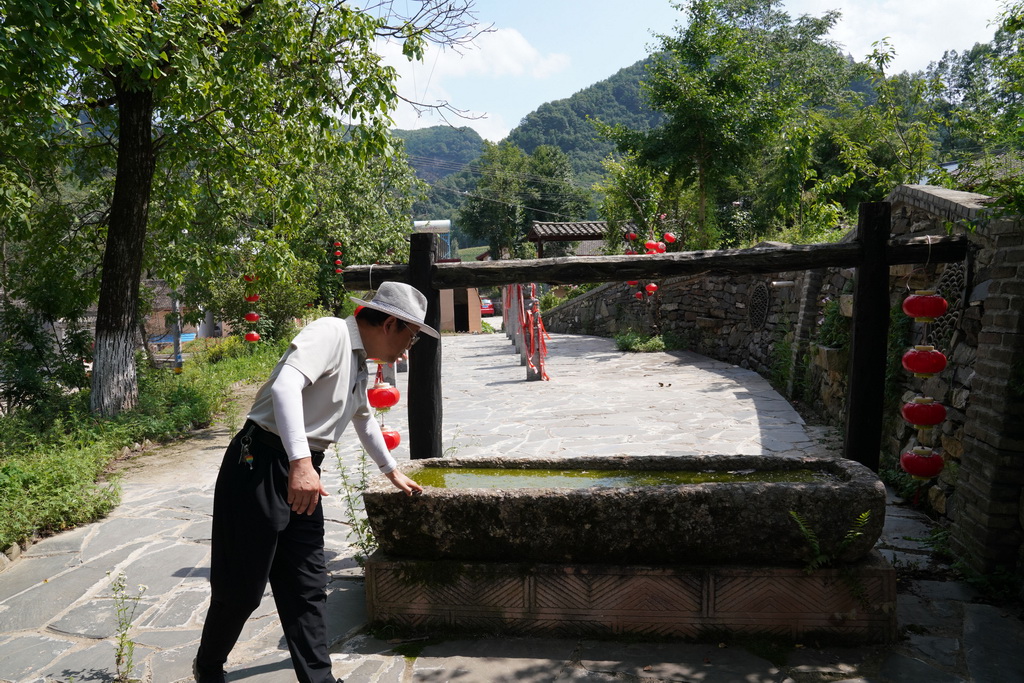 7月14日,在甘肃省陇南市徽县大河店镇青泥村,徽县博物馆文博副研究馆员曹鹏雁在介绍一件古代石马槽。新华社记者 马宁 摄