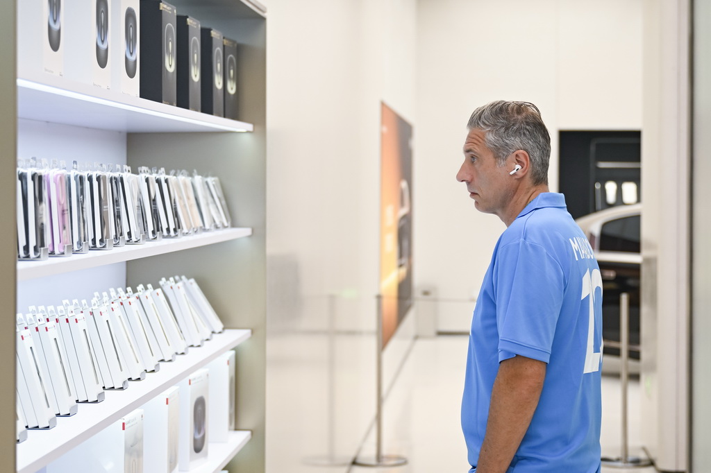 7月17日，一名外国游客在位于上海市南京路步行街的华为商店里浏览电子产品。新华社记者 陈浩明 摄