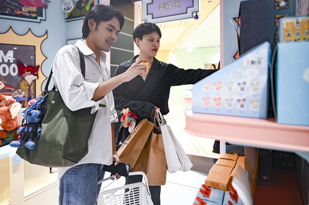 7月17日,两名泰国游客在位于上海市南京路步行街的一家潮玩店里挑选商品。新华社记者 陈浩明 摄