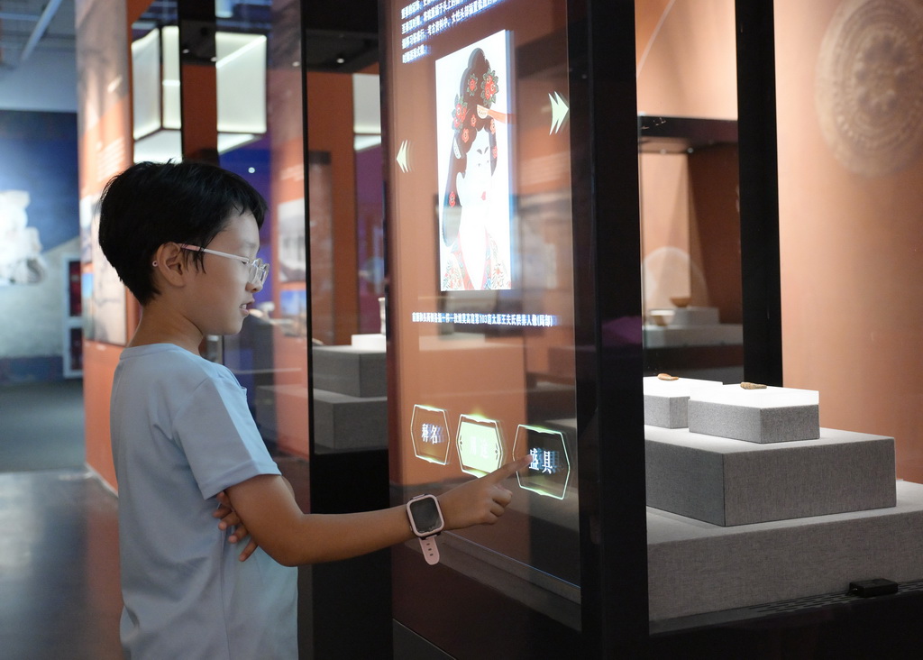 7月28日，一名小朋友在展厅内体验文物智能展柜。