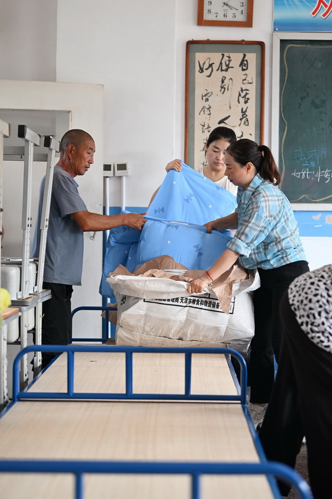 7月28日，人们在天津市蓟州区下营镇初级中学安置点铺设被褥。