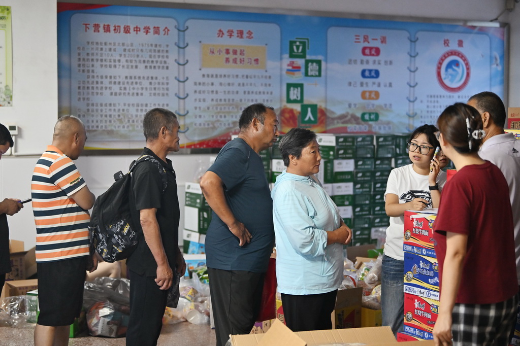 7月28日，集中安置群众在天津市蓟州区下营镇初级中学排队领取物资。