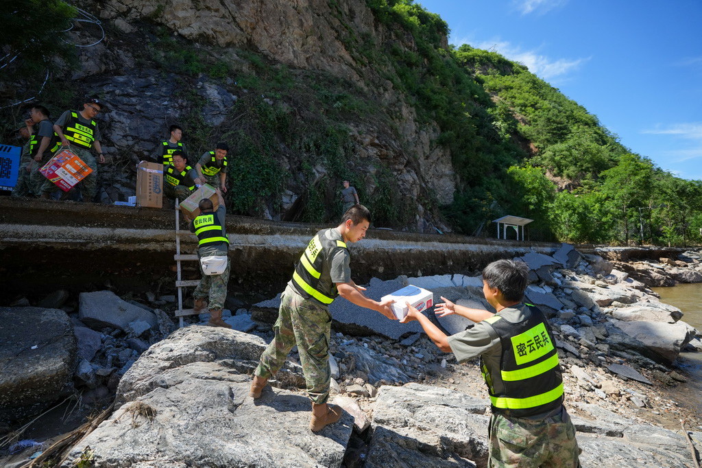 7月30日,在密云区冯家峪镇三岔口村,救援人员为村民运送生活物资。