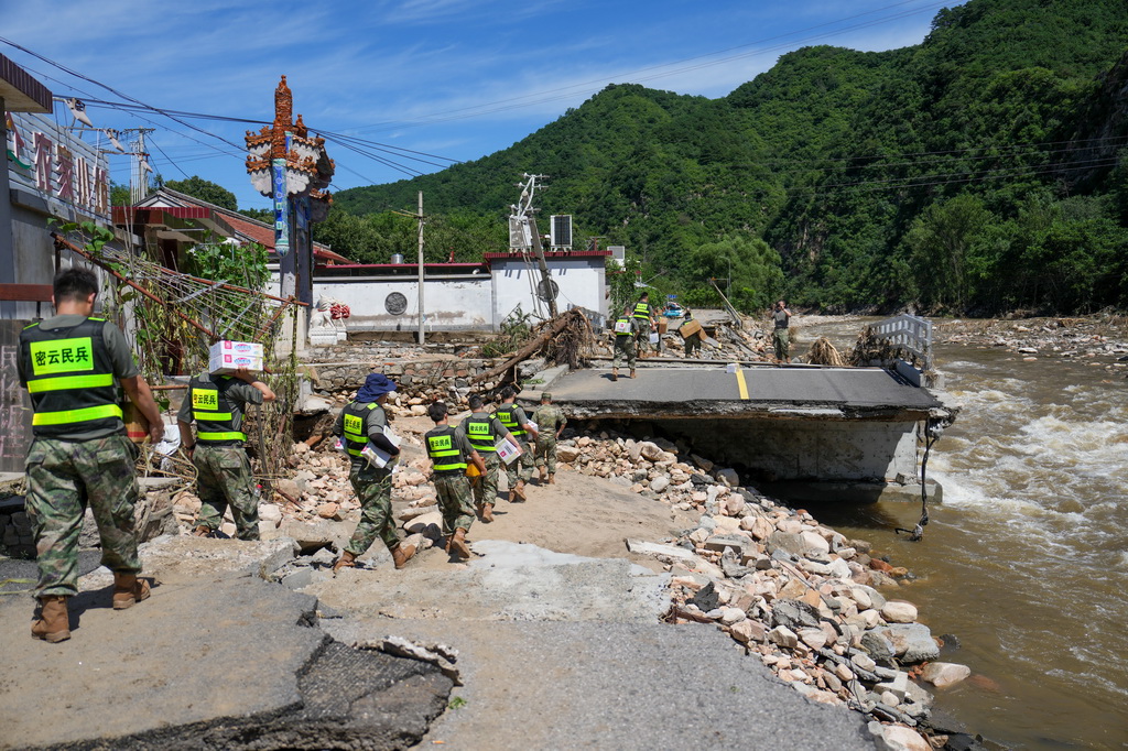 7月30日，在密云区冯家峪镇，救援人员为道路被阻断的村庄运送物资。